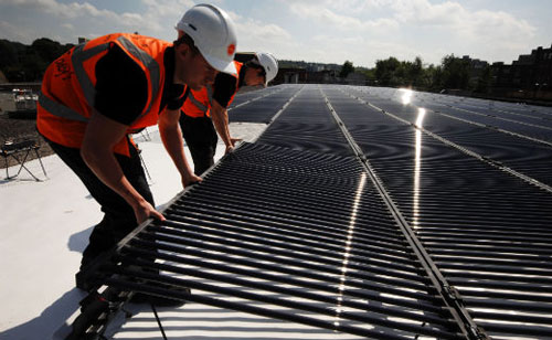 Photovoltaic solar panels being installed on the roof of Sainsbury’s supermarkets.